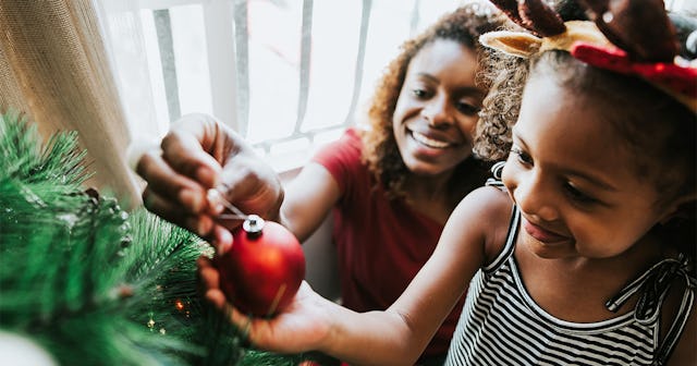 Mother and daughter putting ornaments on a Christmas tree