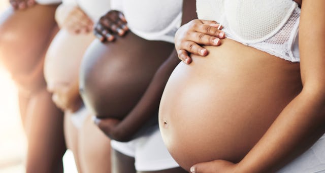 Four expectant mothers proudly displaying their baby bumps