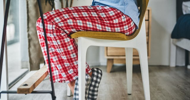 A woman sitting in checkered pajamas at home during lockdown