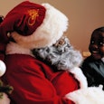 Black Santa Claus giving a Christmas gift to a young boy