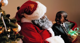Black Santa Claus giving a Christmas gift to a young boy