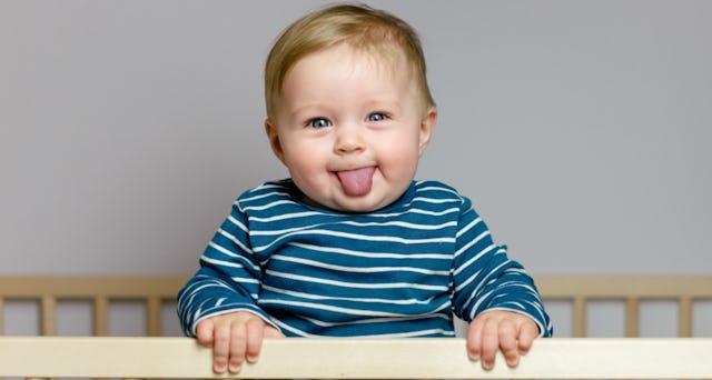 A baby boy sticking out his tongue and laughing.