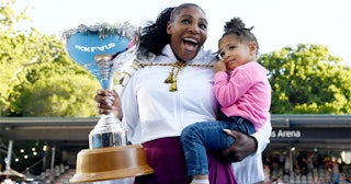 Serena Williams, who wrote her first kids book holding her daughter and a trophy while smiling 