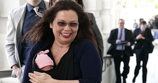 US Senator Tammy Duckworth holding her newborn in arms while having a big smile on her face.