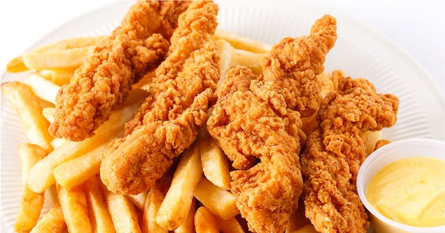 Chicken tenders with fries and dip on the side served on a white plate