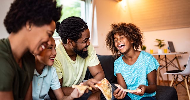 Parents having fun with their kids while eating pizza and laughing.