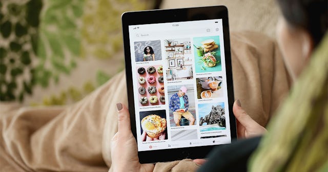 A young female looking at a tablet screen that shows the trending search from the Pinterest app