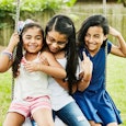 Three little girls who are sisters, two of them getting along with the one who is autistic