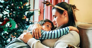 A mother hugging her son next to a Christmas tree during holidays