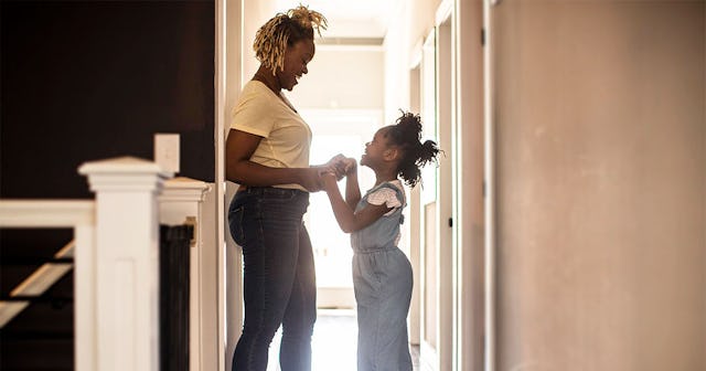 A mom standing and holding hands with her kid whom she lets play hooky