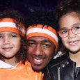 Nick Cannon with his two daughters smiling for a photograph 