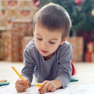 Child coloring in front of Christmas tree — Christmas tree coloring pages