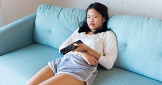 A woman sitting on a couch and watching TV