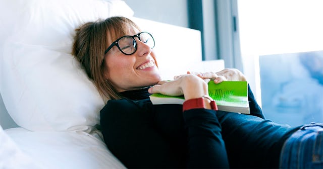 A woman lying down in bed holding one of her favorite books of 2021 on her chest