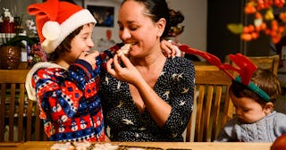 Mother and two kids sitting at the dining table, the kids are in Christmas clothes while the mother ...