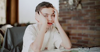 A boy who is a relentless ranter, holding his hands on the sides of his head while sitting in a chai...