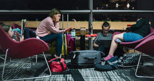 A mother, a father and their two children sitting at an airport lounge due to a flight delay