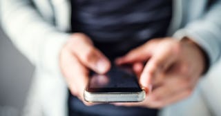 A close-up of a man scrolling on his phone.