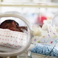 A newborn baby lying down in a NICU bed