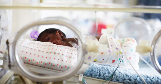 A newborn baby lying down in a NICU bed