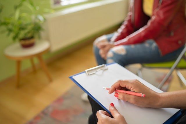 A doctor taking notes about a kid's adolescent eating disorder during an appointment.