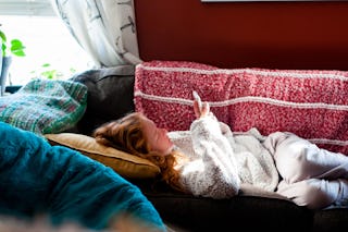 Teenage girl laying on a red sofa texting, dealing with heartbreak