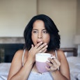 Image of a woman at home yawning over morning coffee