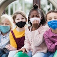 Four children on playground wearing masks to protect against Covid-19