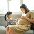 Pregnant woman playing with daughter at home