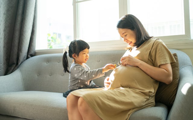 Pregnant woman playing with daughter at home