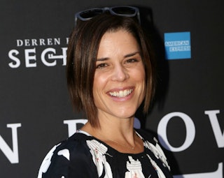 Neve Campbell, smiling while posing on the red carpet