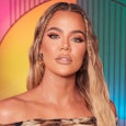 A picture of Khloe Kardashian standing in front of a multi-colored background.