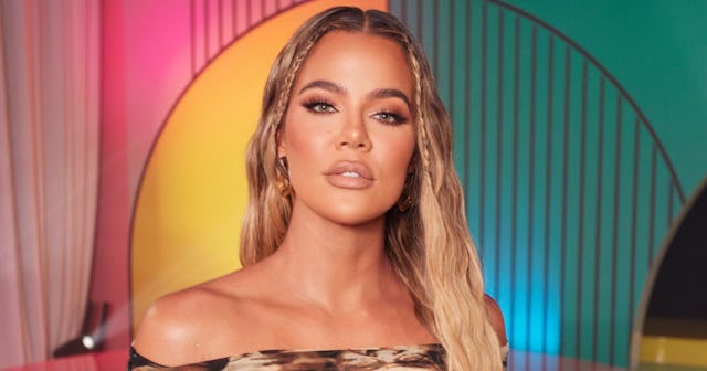 A picture of Khloe Kardashian standing in front of a multi-colored background.