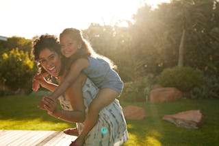 Mother gives her daughter a piggyback ride outdoors