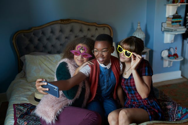 Three tween girls taking a selfie at a sleepover