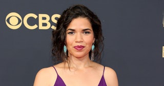 Actress America Ferrera posing while wearing a purple dress, blue earrings and purple lipstick, and ...