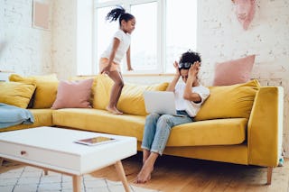 Mother holding her hands on the head because she is tired of being flexible while her daughter is ju...