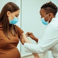 Woman getting vaccinated by a doctor at the hospital, since research showed no effect on fertility  