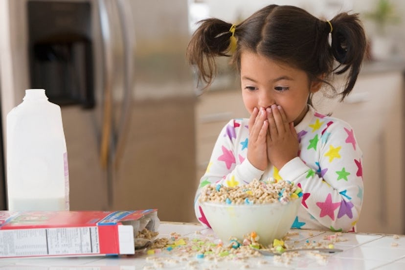 A little girls looks on in shock at spilled cereal.