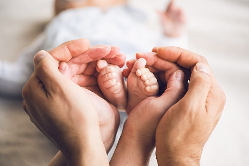 Parents cup their baby's feet in their hands.