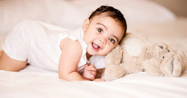 A cute baby girl cuddles with her teddy bear.