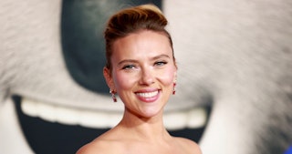 Scarlett Johansson, with red earrings, smiling and posing during a red carpet event