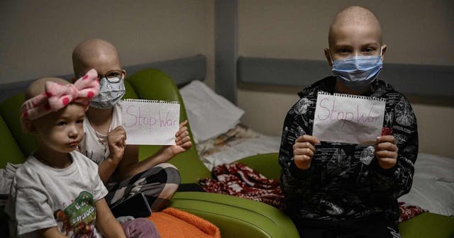 Children struggling with cancer holding signs that says "Stop War" in a bomb shelter in Kyiv