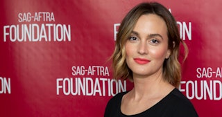 Actress Leighton Meester posing and smiling with natural makeup spiced up with red lipstick.