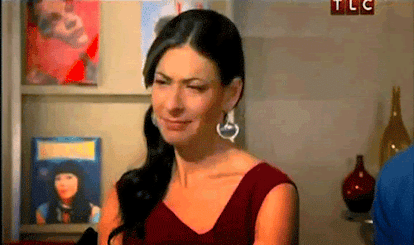 Gif of fashion designer Stacy London wearing a red dress and turning her head with a "TLC" sign in t...
