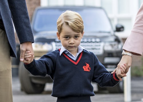 A closeup of Prince George in his school uniform, walking while holding hands with Prince William an...