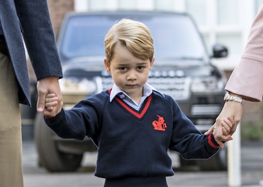 A closeup of Prince George in his school uniform, walking while holding hands with Prince William an...