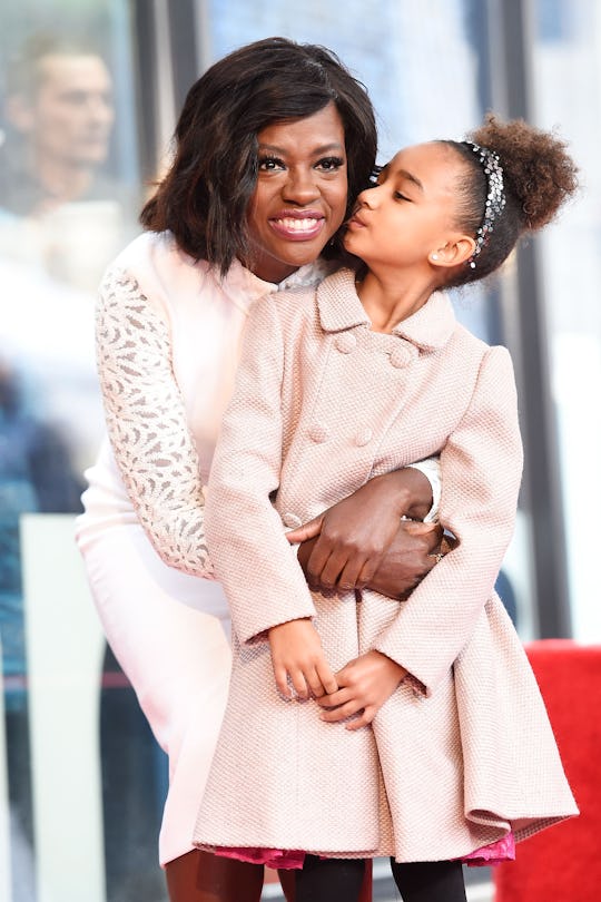 Viola Davis in a white dress hugging her daughter who's wearing a pink coat.