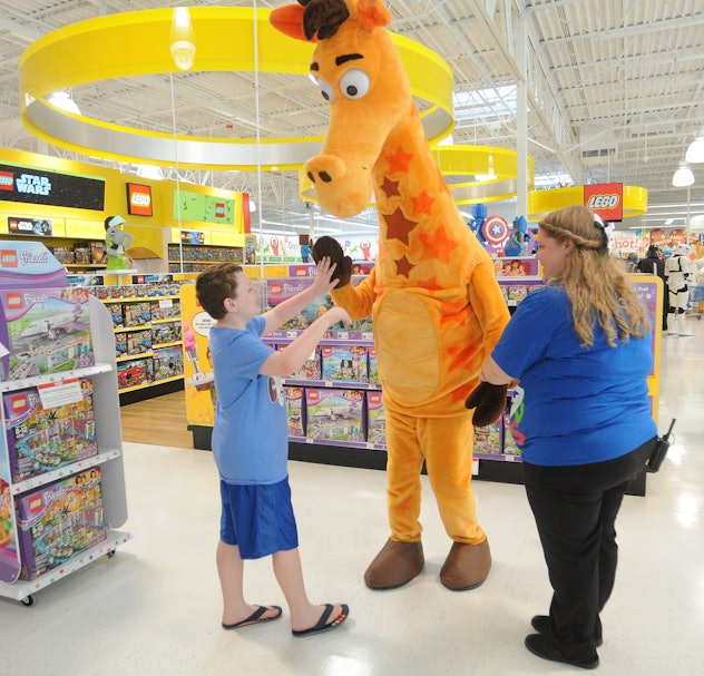 A boy giving a high five to a big giraffe mascot