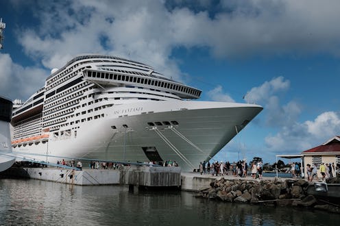 A large cruise ship at the waterfront anchored with people boarding